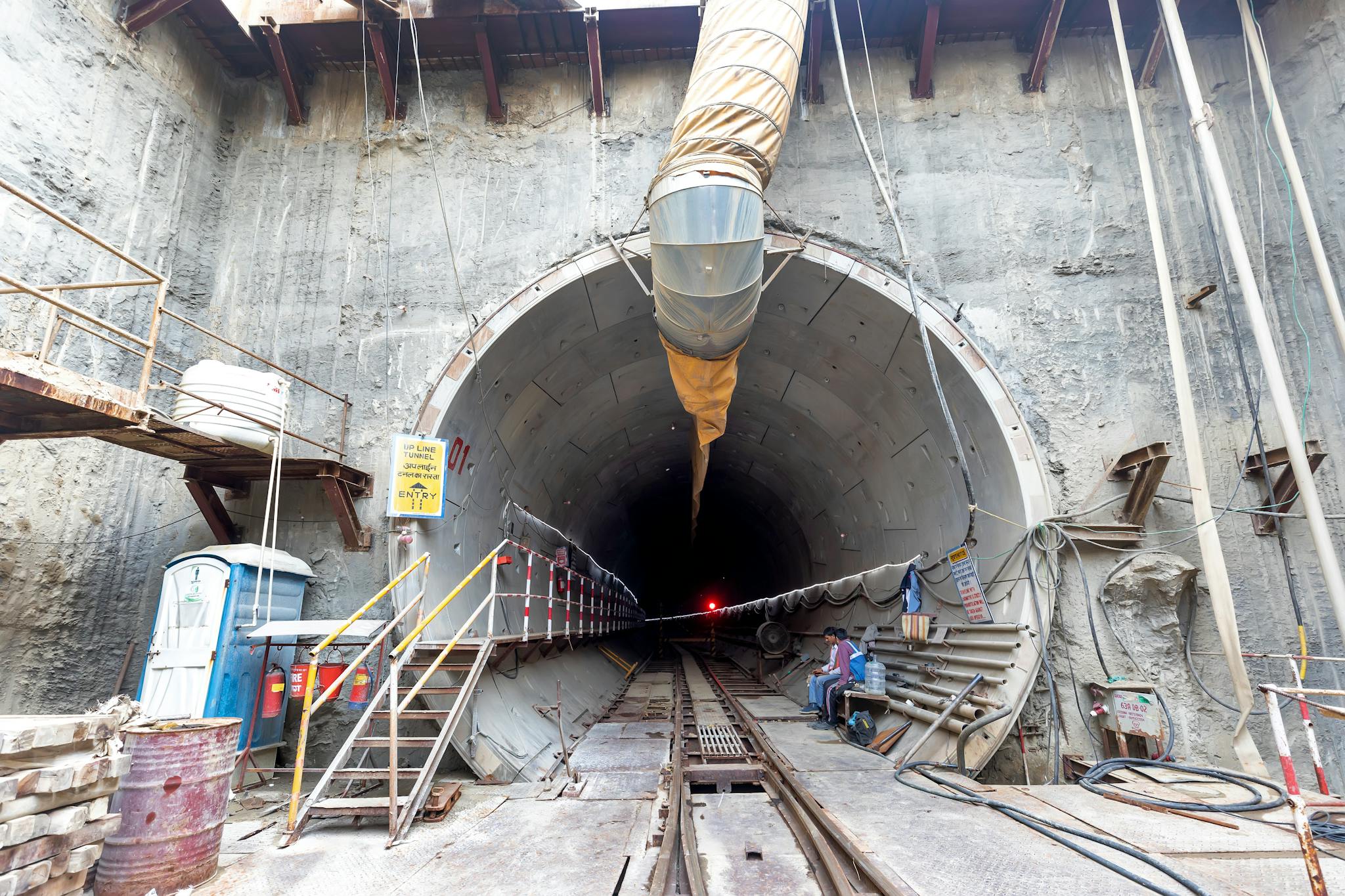 Industrial tunnel entrance under construction with heavy machinery and safety equipment.
